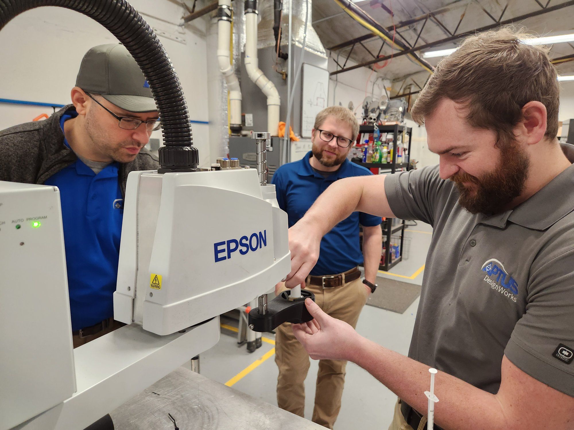 Three APTUS engineers working together on a robot in the shop